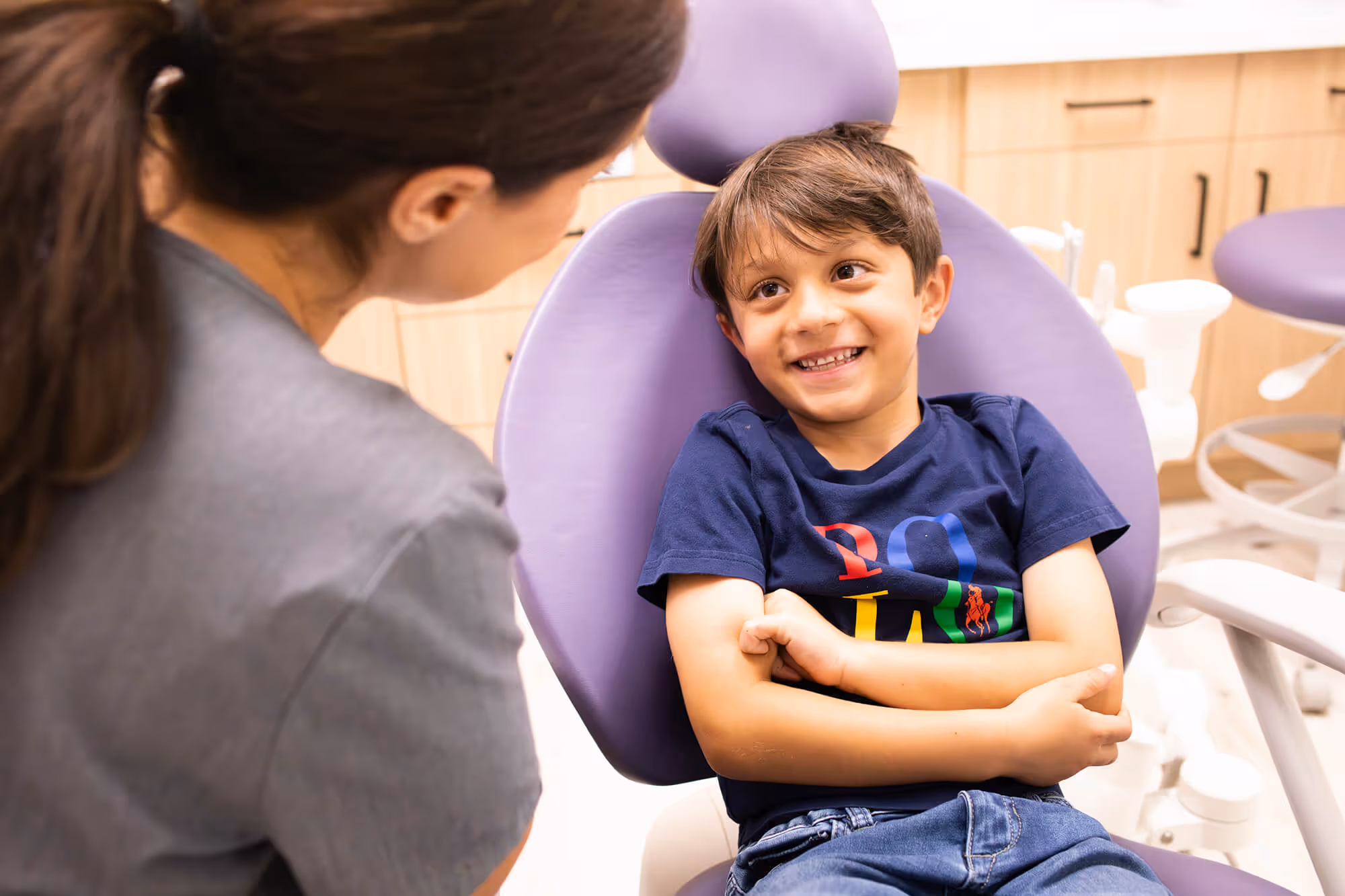 A young boy sitting in a chair with his arms crossed.