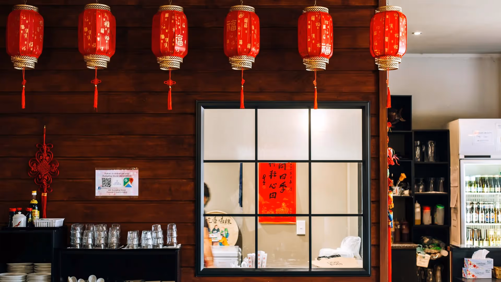 Alt text: "Interior of a cozy Hamilton restaurant featuring traditional red lanterns and a warm wooden wall, showcasing local Chinese cuisine. The welcoming atmosphere supports community engagement and highlights local dining experiences."