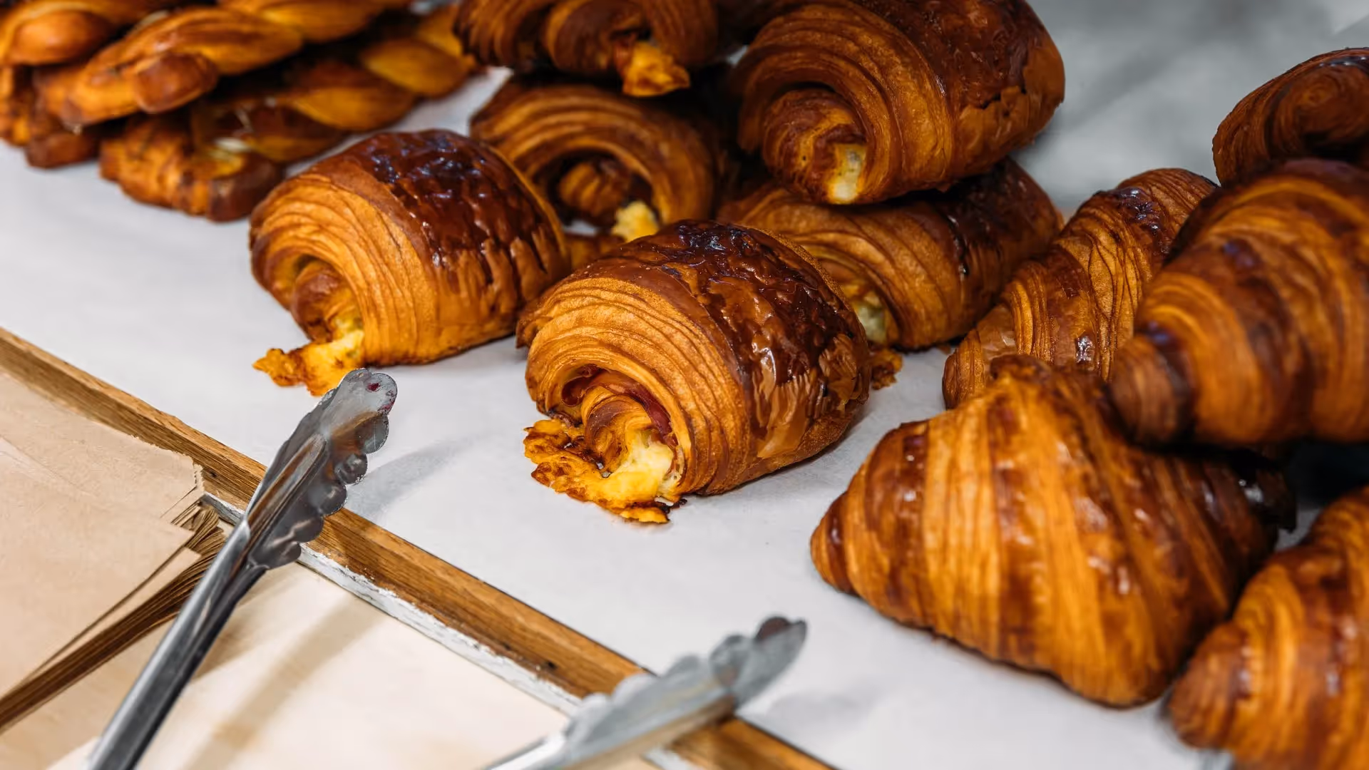 Freshly baked golden croissants and pastries displayed on a counter, showcasing Hamilton's local culinary delights. Love the Centre promotes supporting local bakeries and enjoying the best community experiences in the heart of the city.