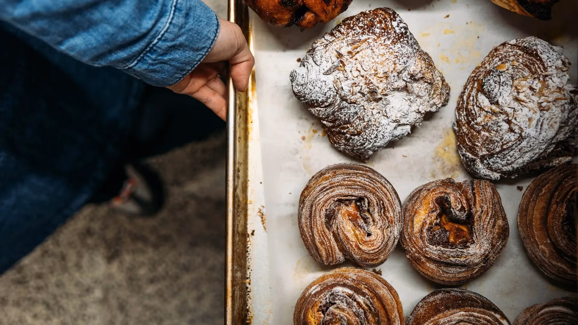 Freshly baked pastries sit in a tray, showcasing delectable chocolate scrolls and flaky croissants. Perfect for enjoying at local cafés in Hamilton, these treats highlight the city’s vibrant food scene and support local bakeries.