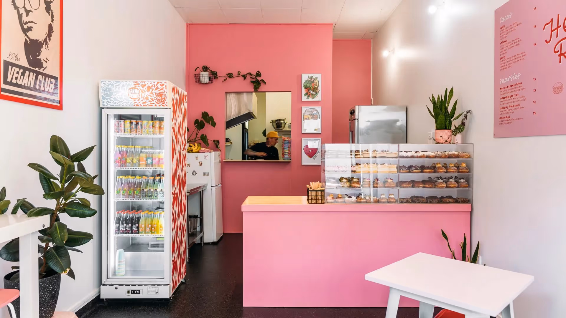 Alt text: "Interior of a vibrant pink bakery in Hamilton, showcasing a display of delicious pastries and desserts. Featuring a drinks fridge and welcoming decor, highlighting local businesses and community charm."