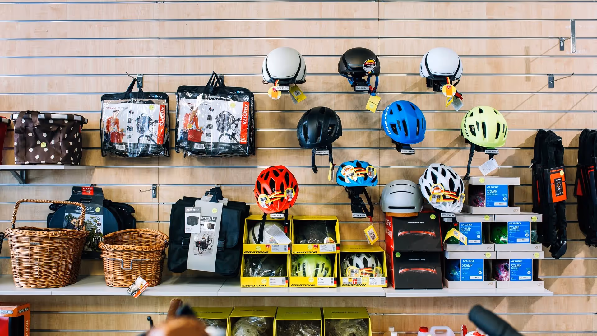 Alt text: "Display of cycling helmets and accessories in a local Hamilton shop, featuring vibrant helmets in various colours, cycling bags, and baskets. Love the Centre supports Hamilton's best businesses and community experience."