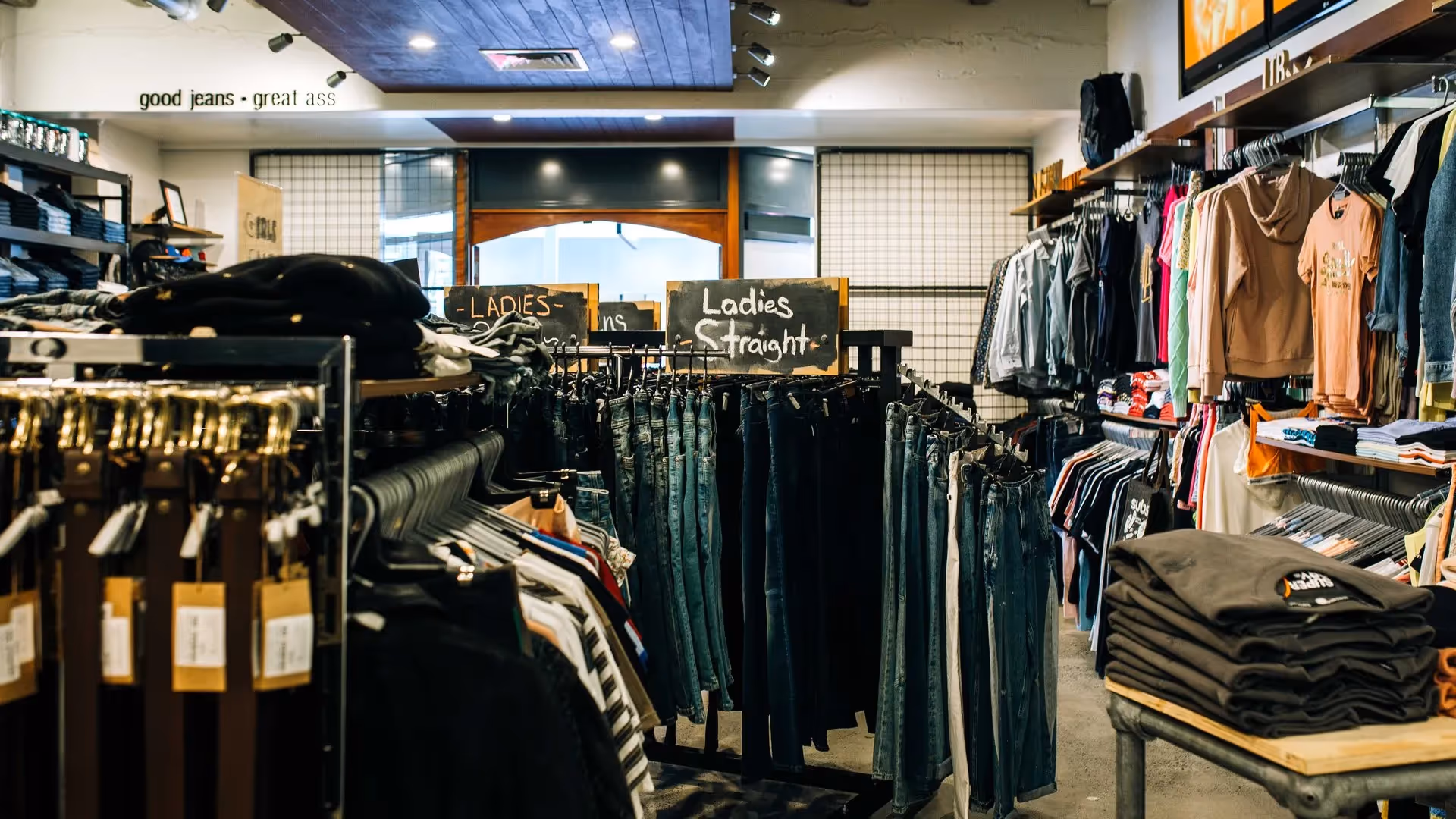 Alt text: "Interior of a local clothing store in Hamilton featuring racks of ladies' jeans and casual wear. The inviting space showcases stylish apparel, supporting local fashion businesses and enhancing the community experience in the heart of the city."