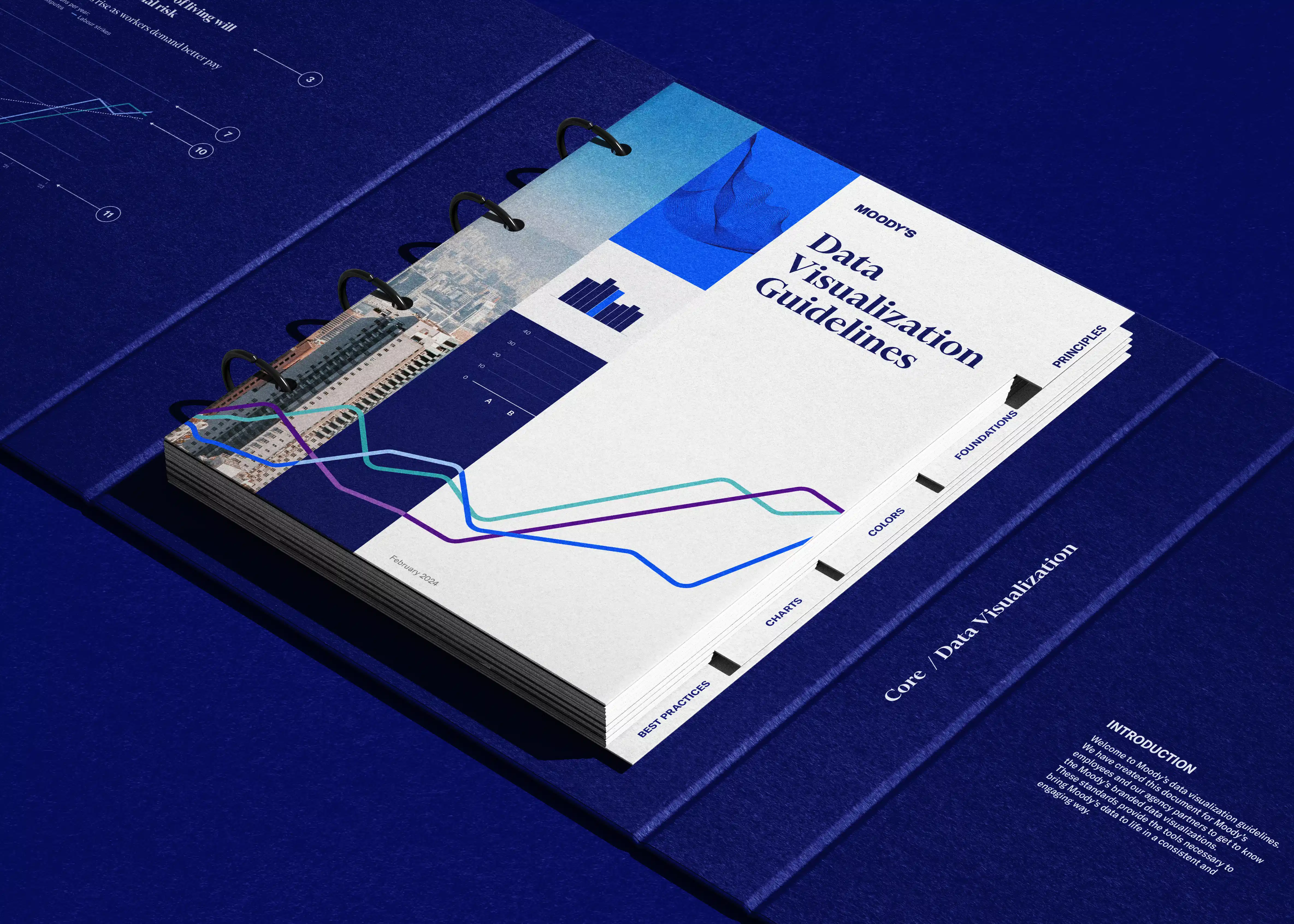 Moody's "Data Visualization Guidelines" document displayed open in spiral-bound format on a blue surface, showing line charts and colorful data visualizations integrated with cityscape photography.