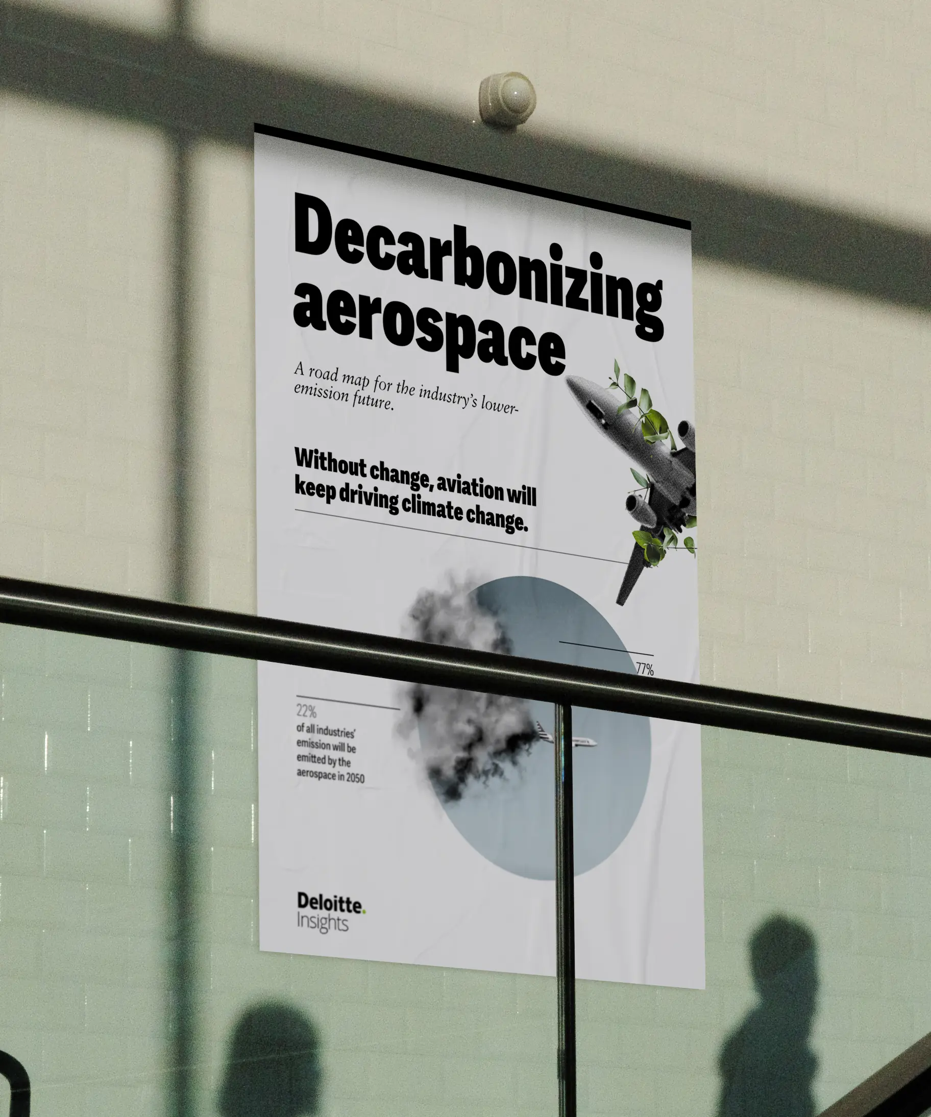 A white poster displays "Decarbonizing aerospace" in bold black text with aircraft graphics and a photography-based pie chart made out of the pollution from an airplane. The poster is mounted on a wall in front of a modern office stairwell.