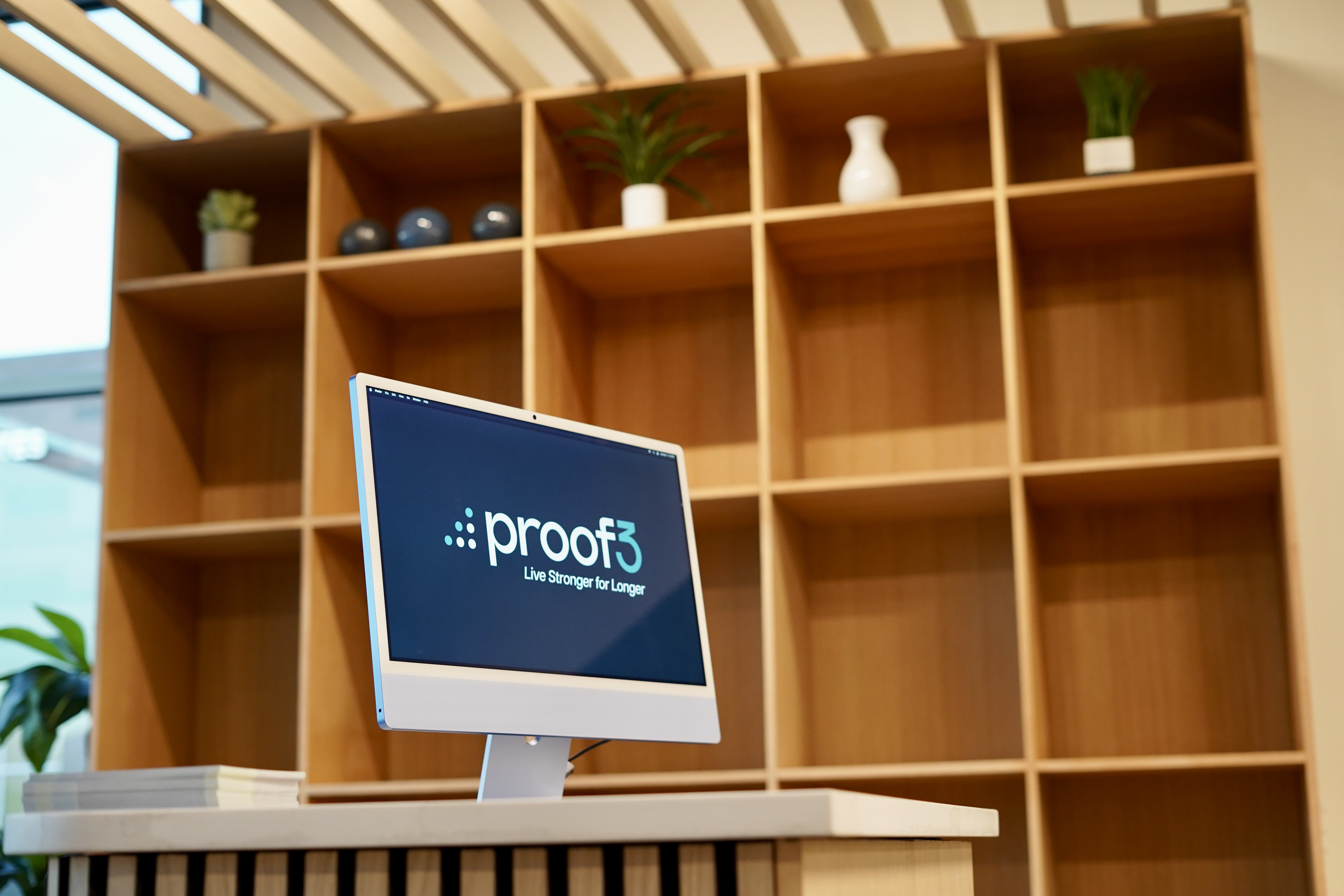 An image showing a side view of the proof3 salt river gym's front area. in the photo, you see a desktop computer, front desk, and behind that you see a cubbie system