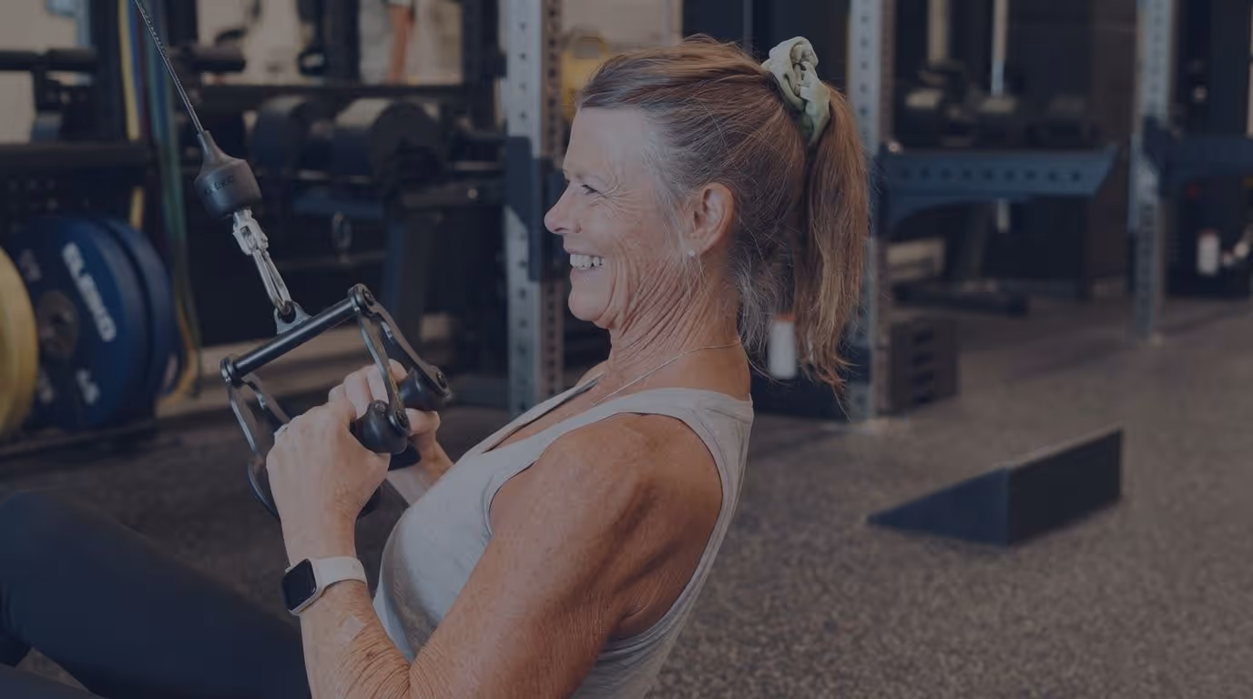 60+ year old female doing a seated cable row.  she's got a smile on her face