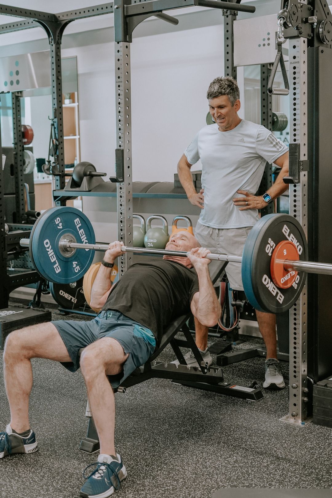 Two men over fifty performing incline barbell bench press at proof3