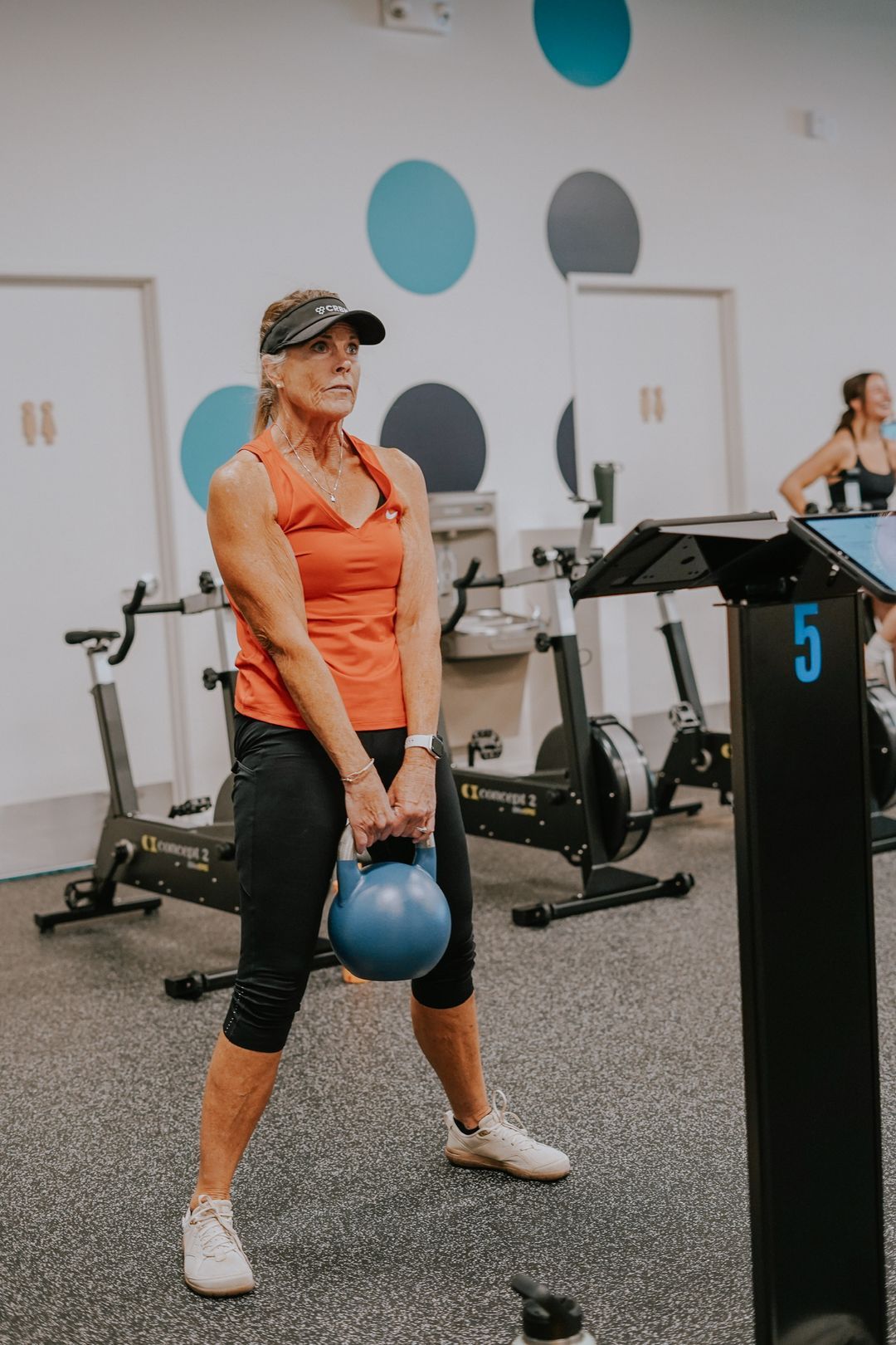 A woman in her seventies performing a kettlebell deadlift at proof3