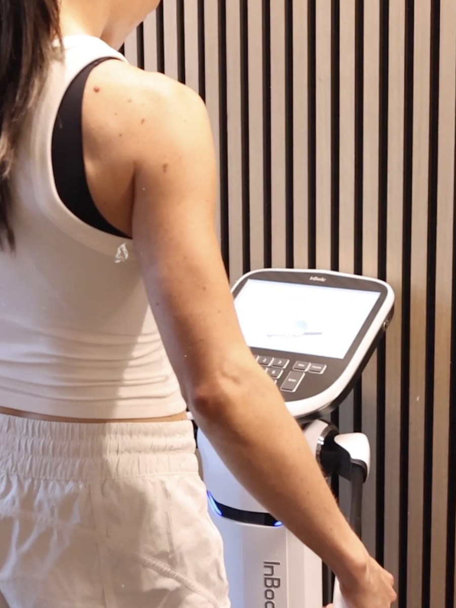 A member standing on the InBody 580 holding the hand grips during a body composition scan