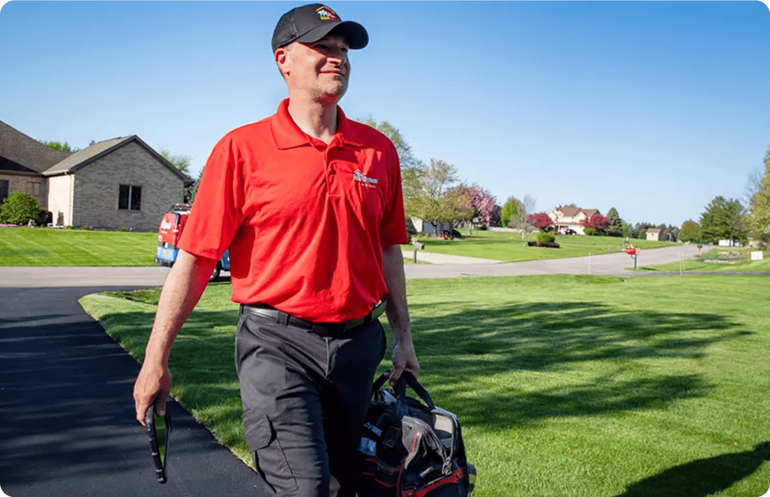 A man in a red shirt carrying a golf bag.
