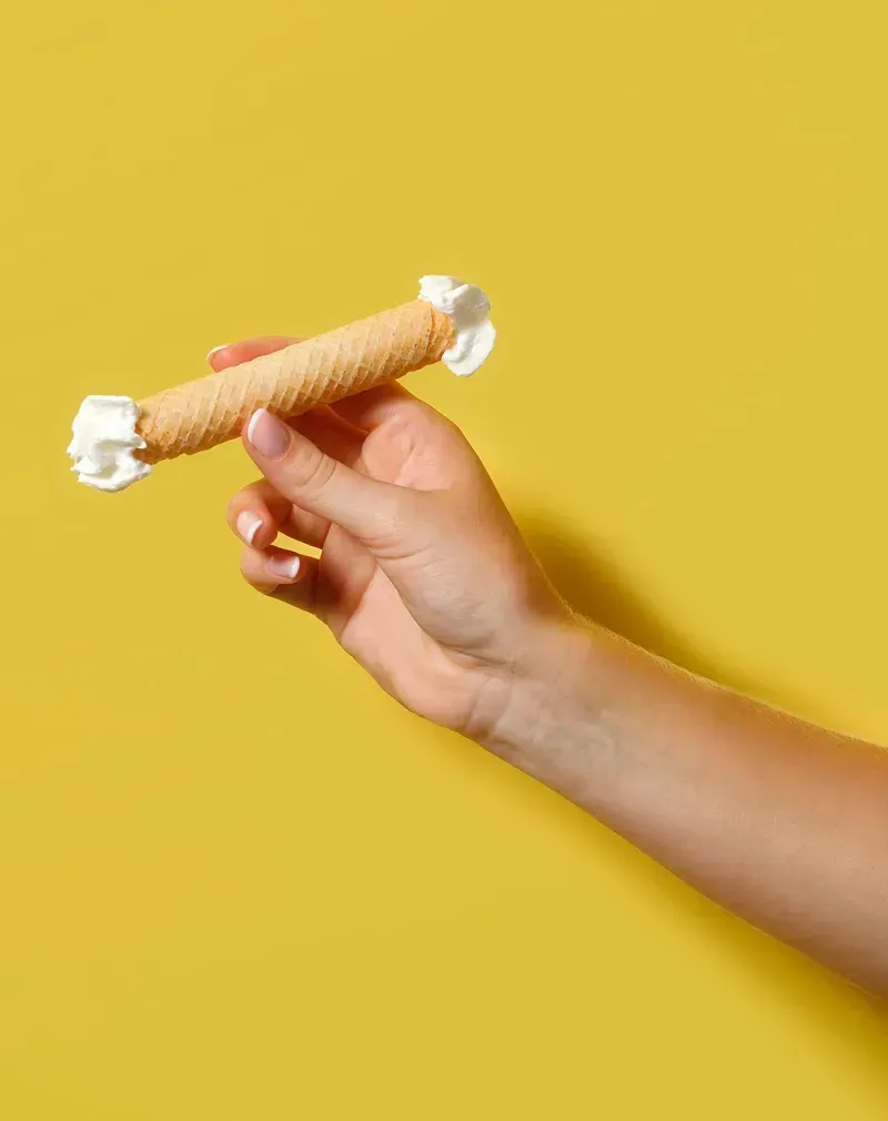 Hand met Vegter's Rolletje gevuld met slagroom