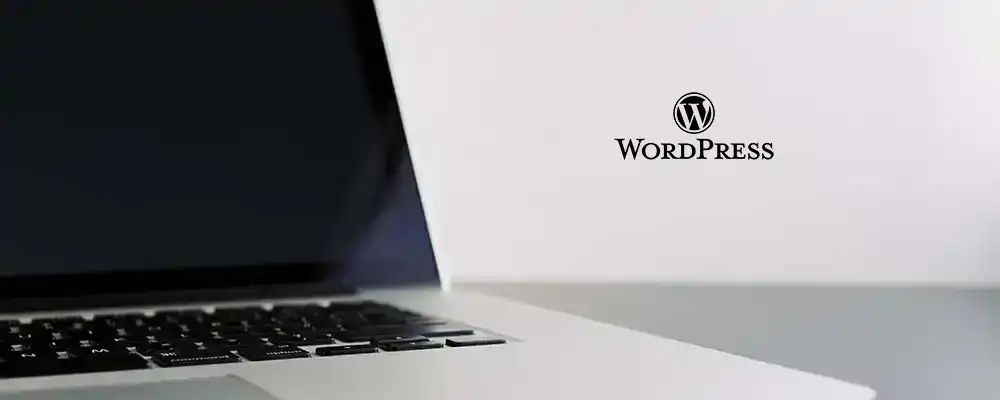 Detaljebilde av en bærbar pc som er åpnet. Wordpress logo rett vedsiden av.