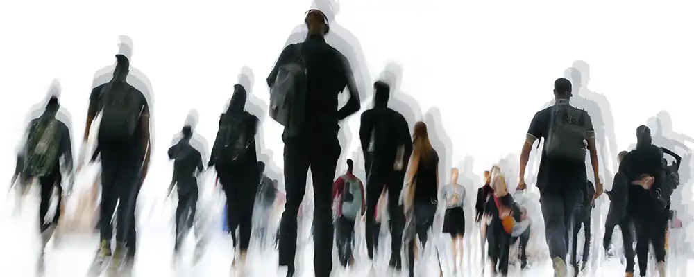Svart hvitt bilde av flere mennesker som går. Menneskene har skygger rundt seg slik at det er ut som om de beveger seg.