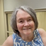 An elderly white woman with cropped gray hair and a warm smile.