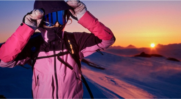Skier in a pink jacket at sunrise on a mountain