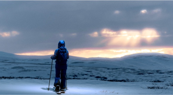 Ski tourer on a snowy plateau under a dramatic sky