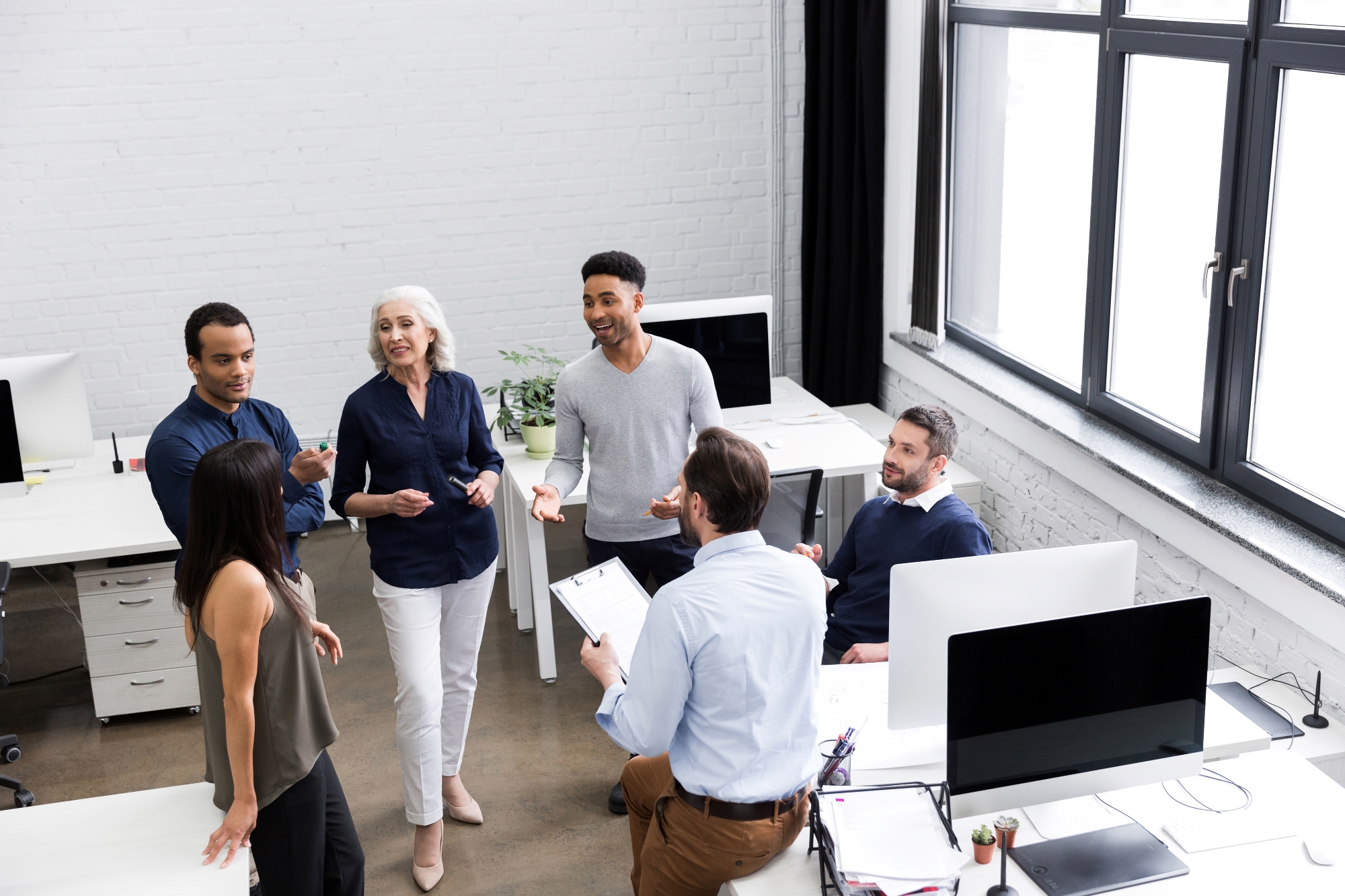 Team aus verschiedenen Generationen diskutiert gemeinsam im modernen Büro – aktive Zusammenarbeit und Austausch in professioneller Arbeitsatmosphäre.