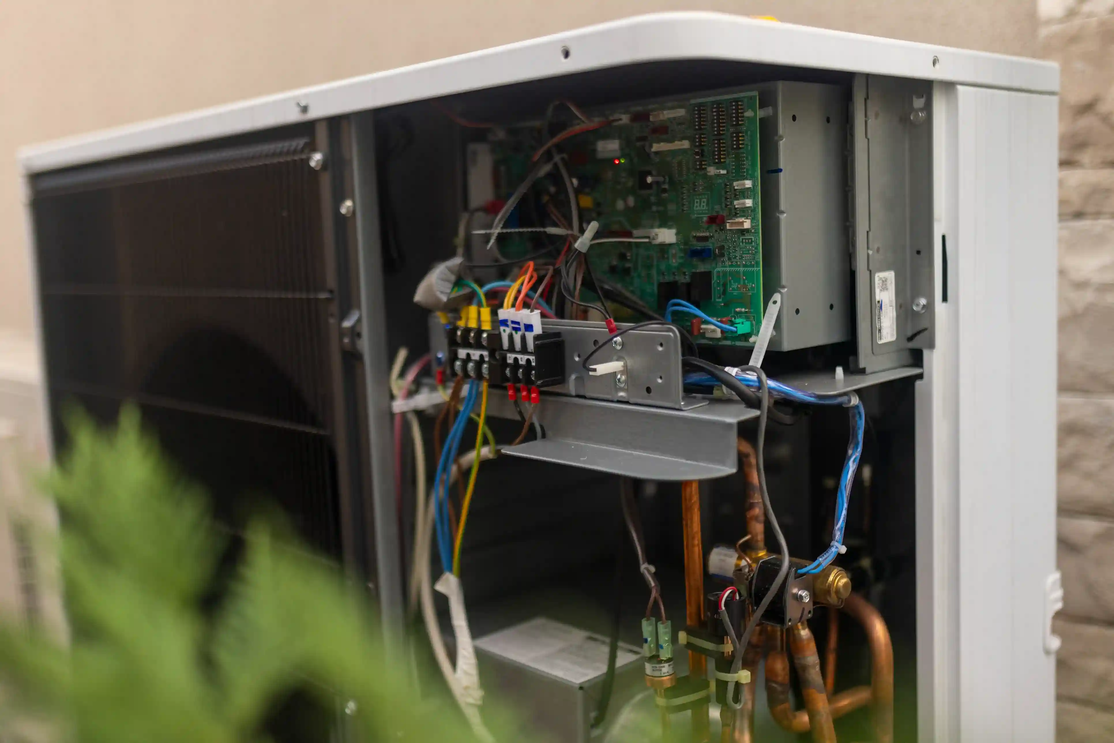 Close-up of the opened side of an outdoor heat pump, revealing circuits and wiring.