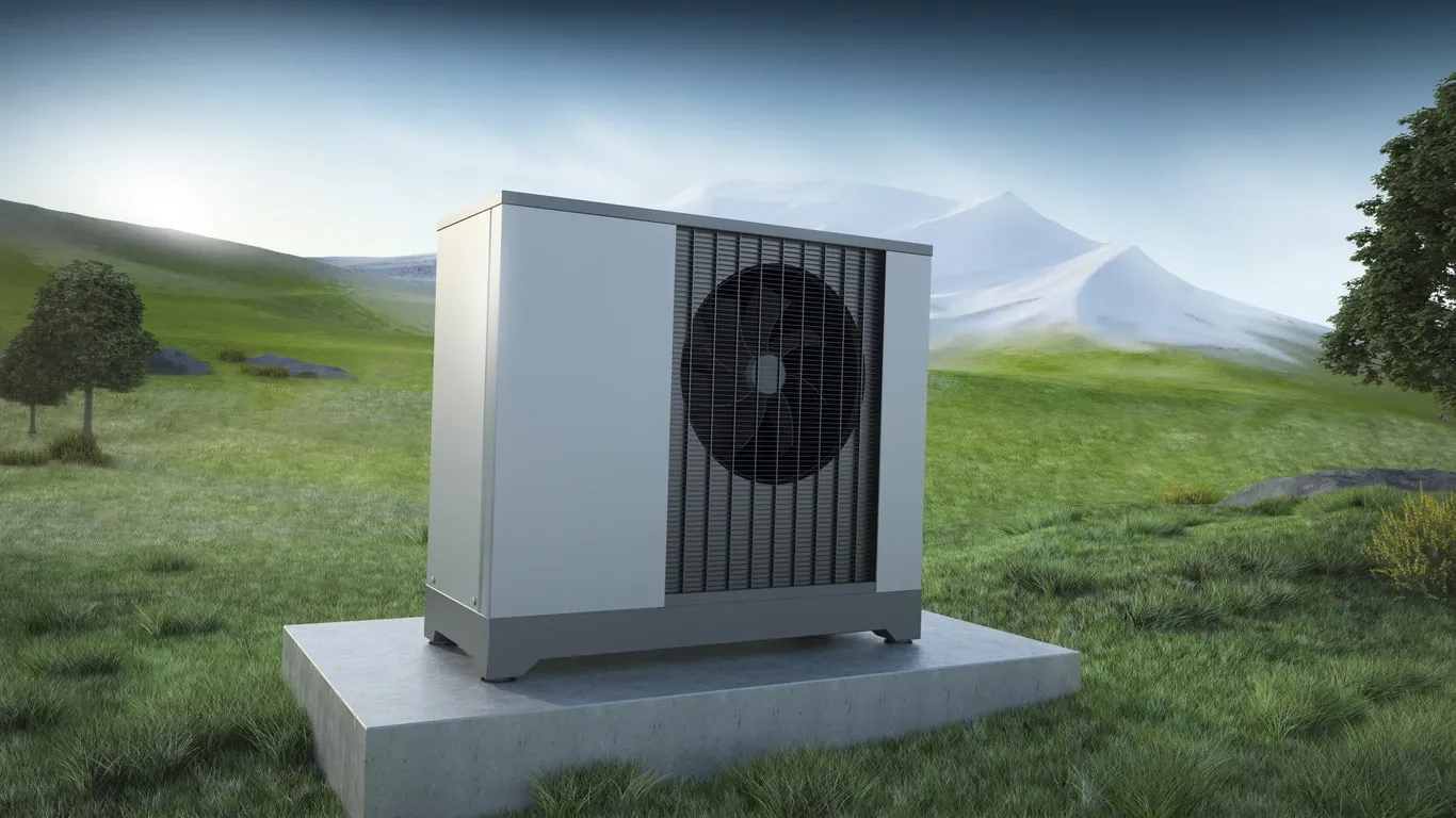 A modern heat pump unit sits on a concrete slab in a green landscape.