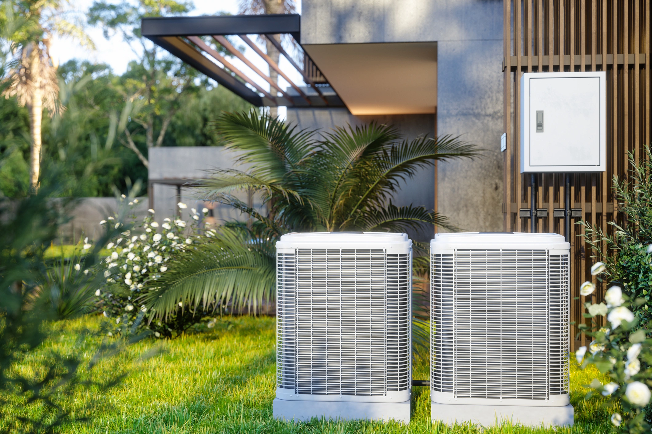 Two air conditioners positioned in front of a residential house.