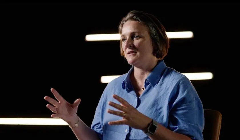 Interview frame: a client speaks in a dark studio set