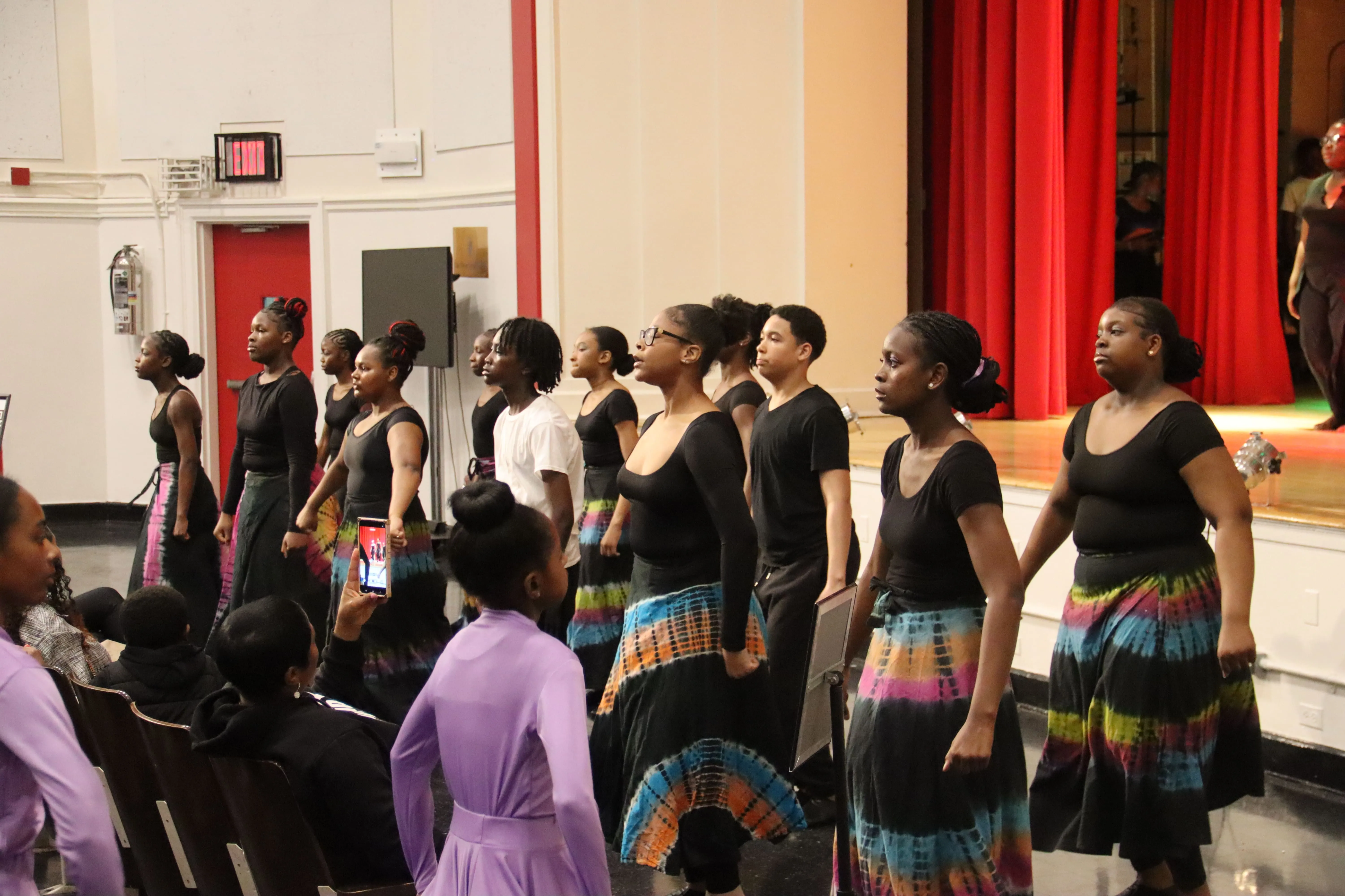 Group of performers lined up on stage in black attire