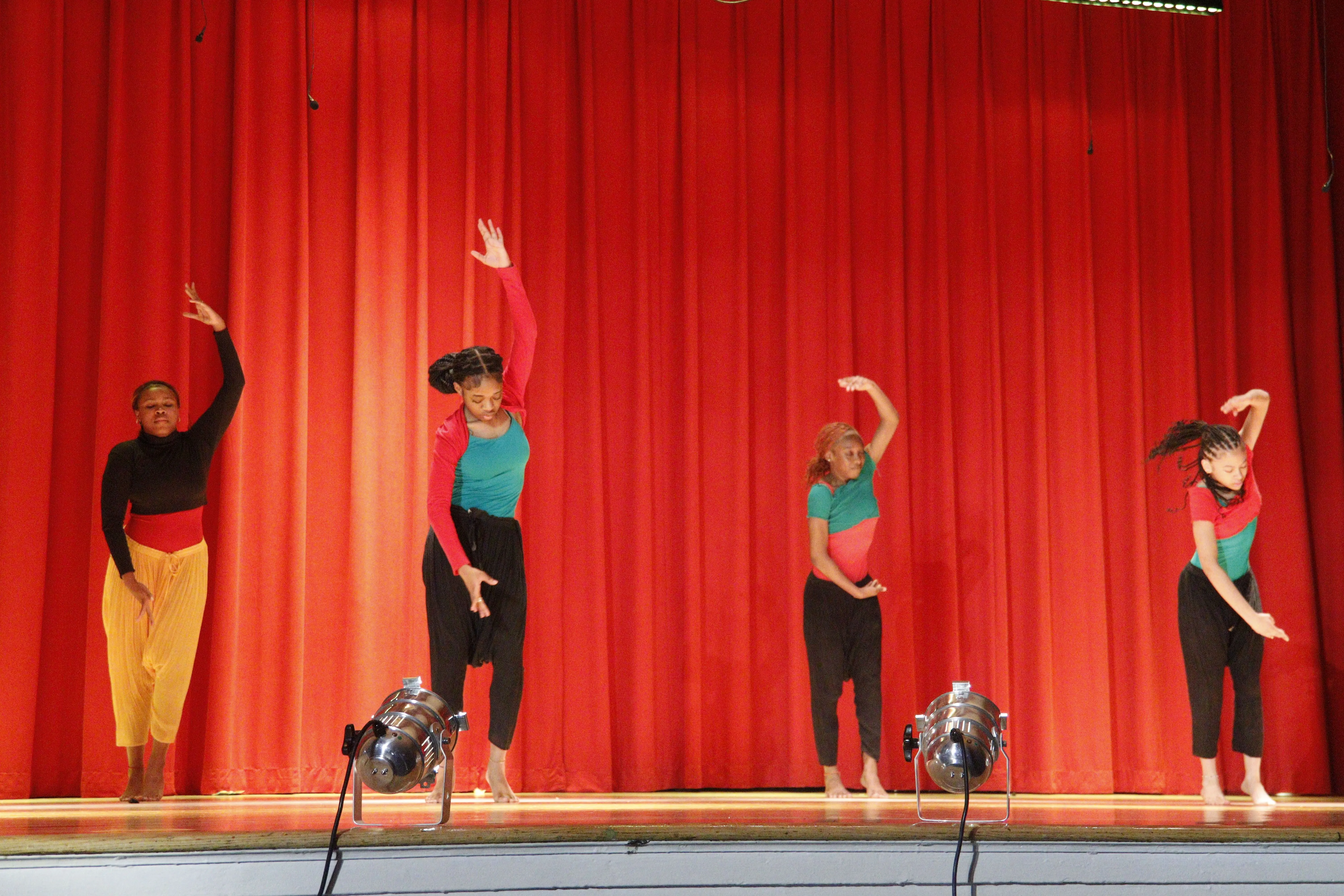 Four dancers performing on stage