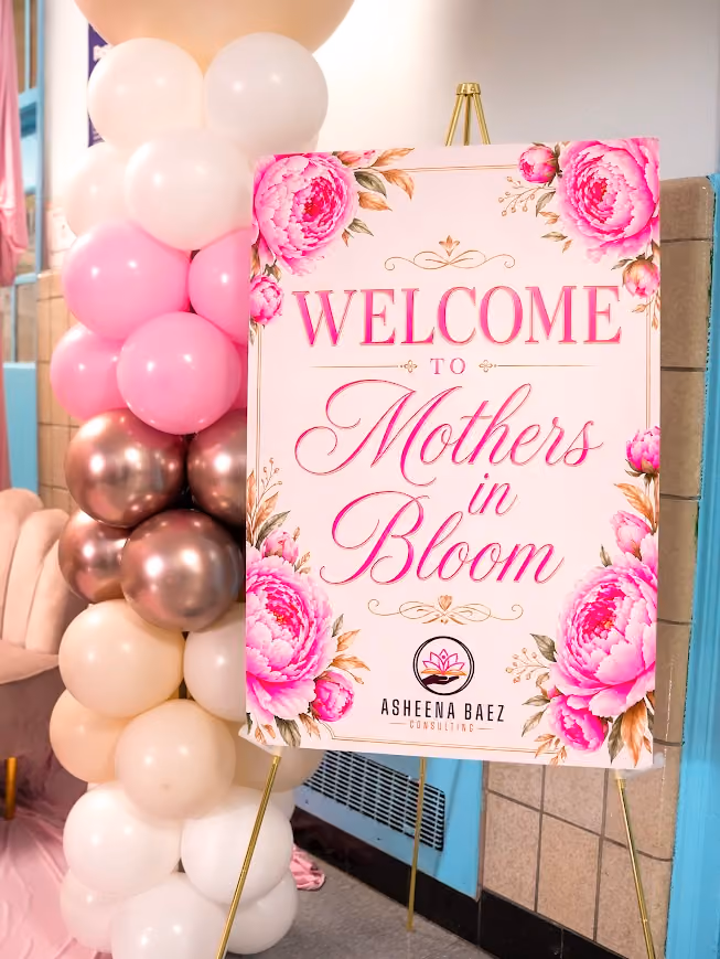 Welcome to Mothers in Bloom event sign with pink floral decor