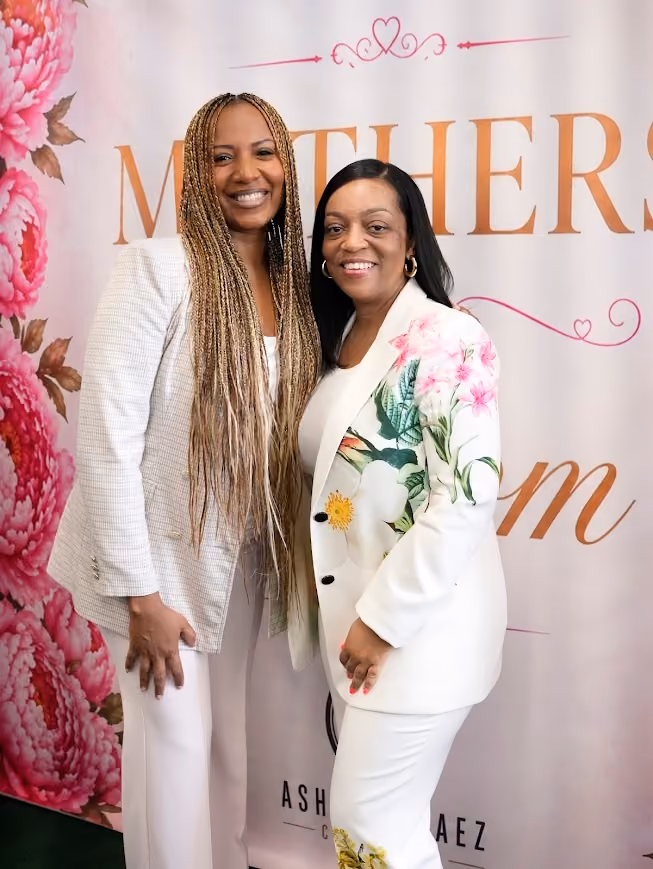 Two women smiling together at a Mother's Day event backdrop