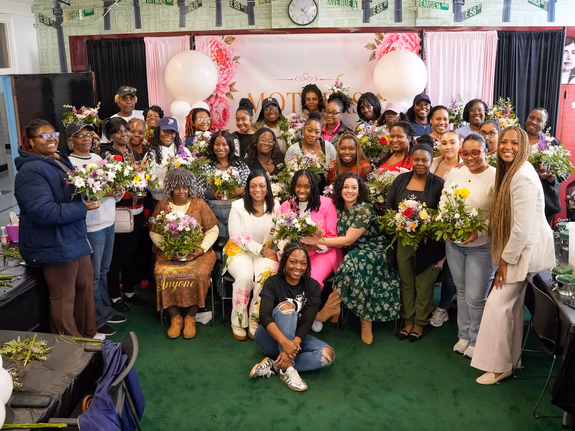 Group of attendees holding floral arrangements at school Mother's Day event
