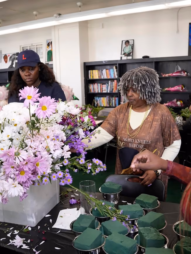 Two adults arranging flowers at a floral design workshop in a classroom