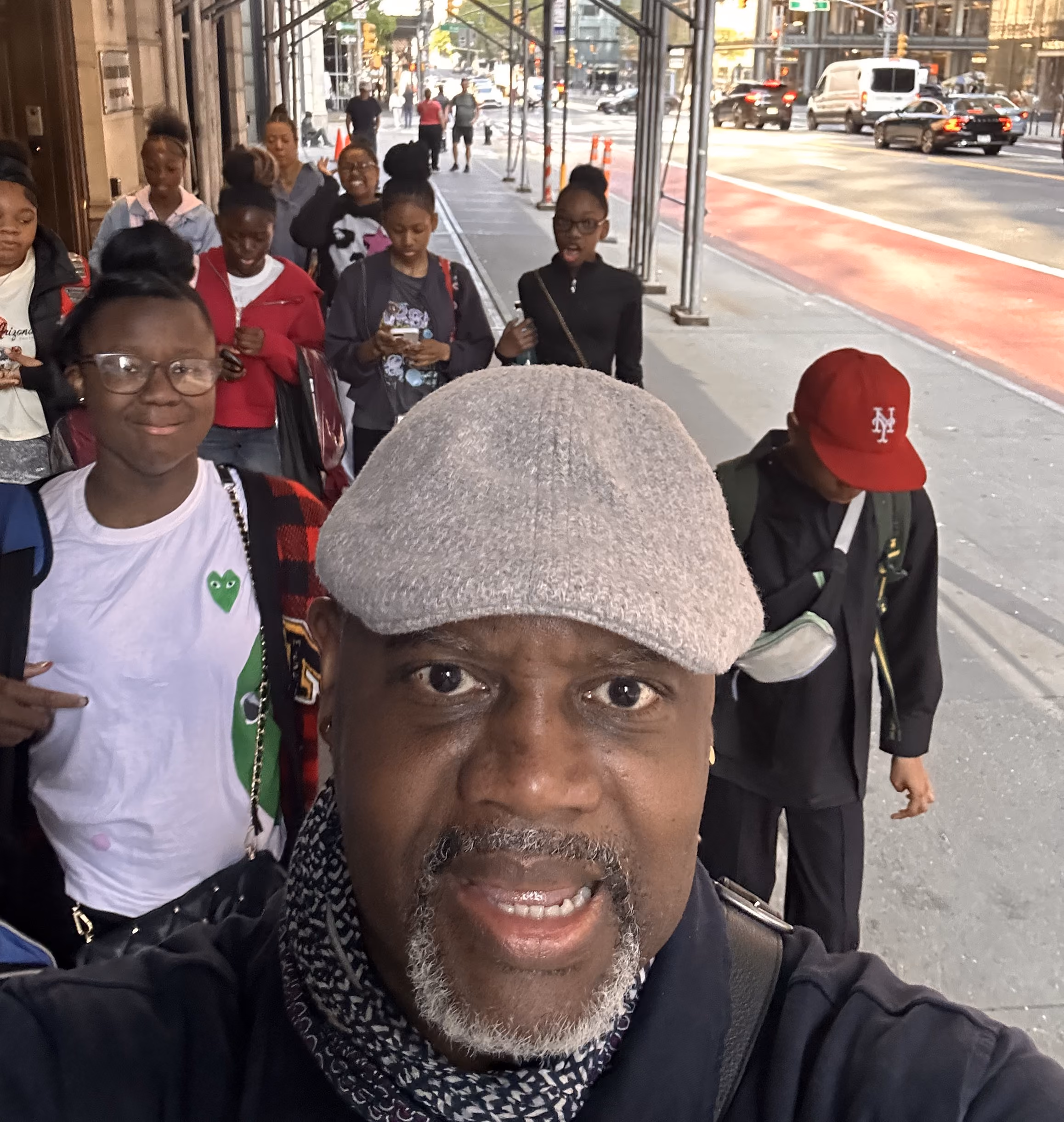 Adult chaperone and students walking together on a city sidewalk
