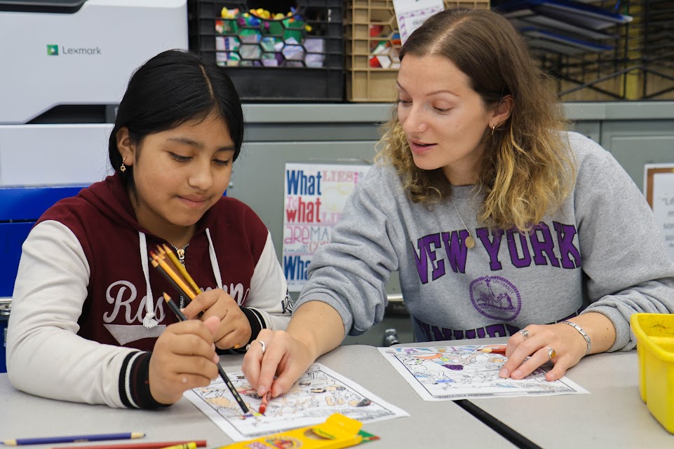 Teacher helping a student color a worksheet in art class