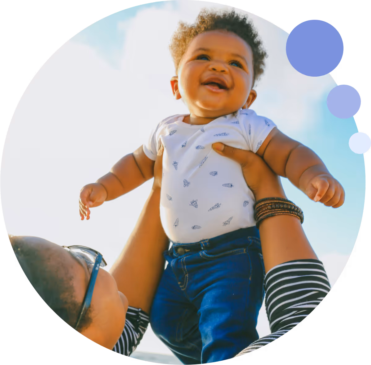 Smiling baby lifted by parent representing family-building with EggFund fertility loans.