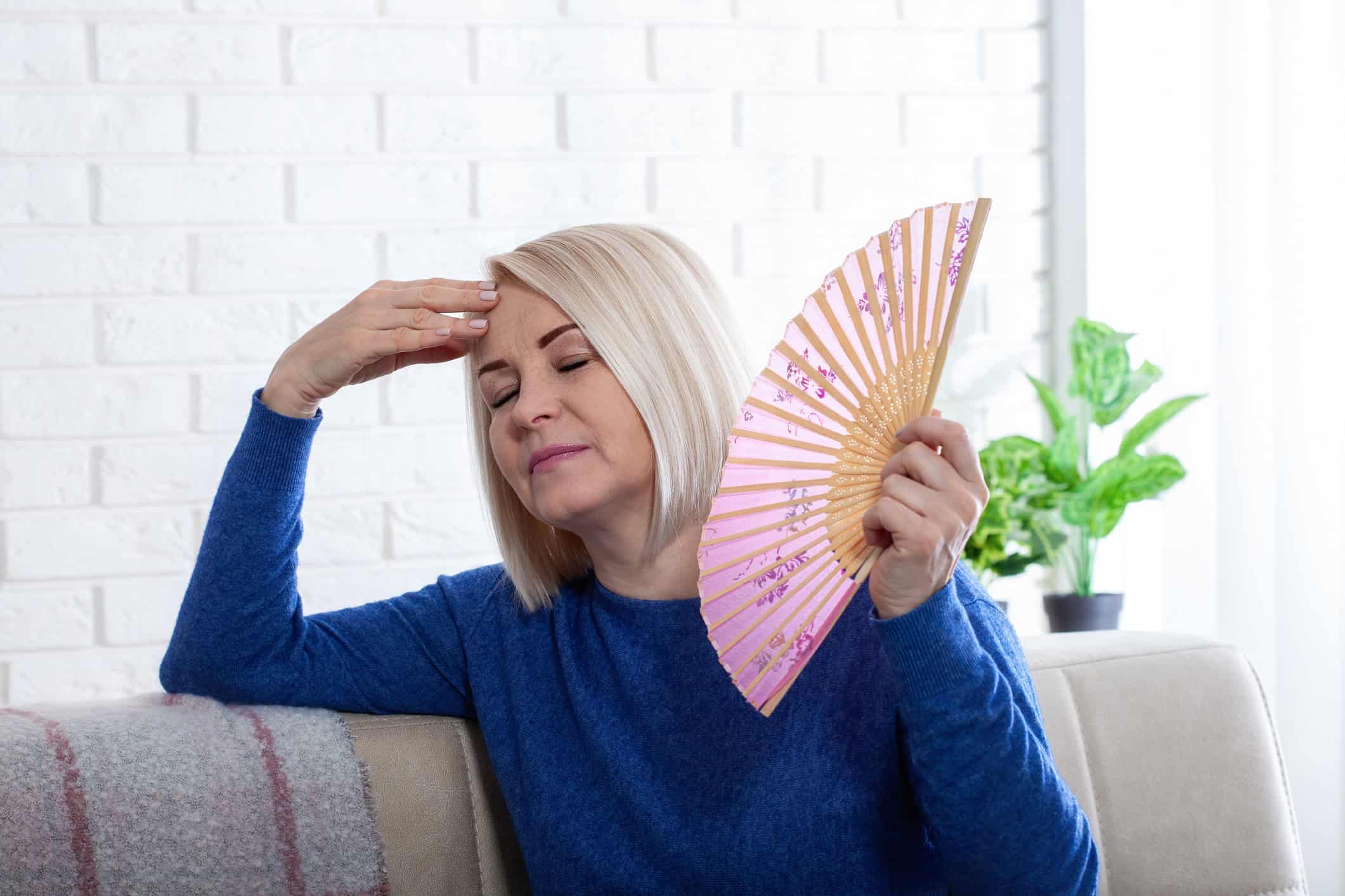 woman cooling herself with hand fan 
