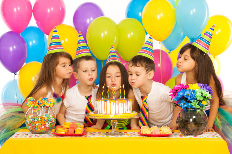 Group of joyful little kids celebrating birthday party and blowing candles on cake. 