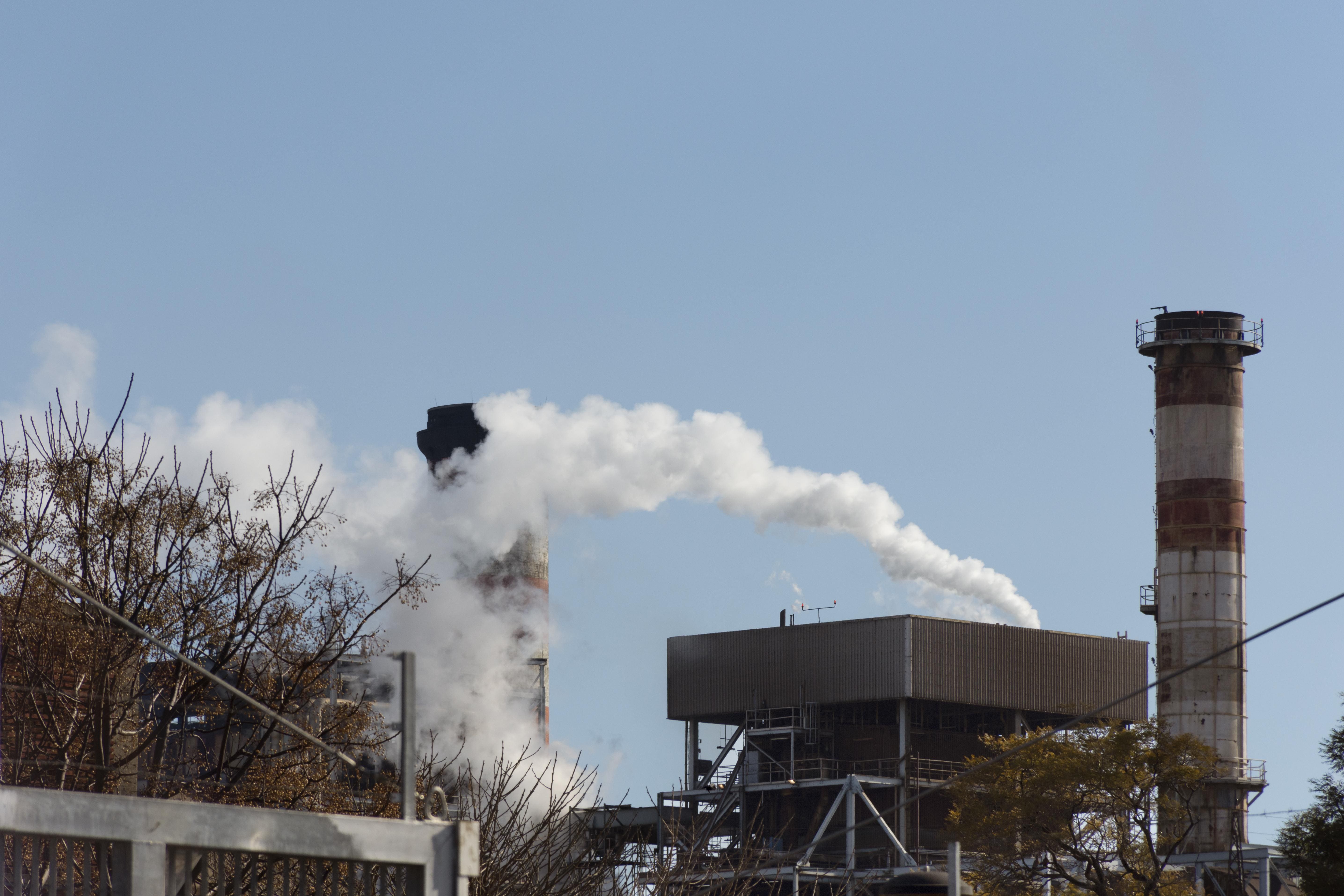 Industrial factory, with two chimneys emitting smoke.