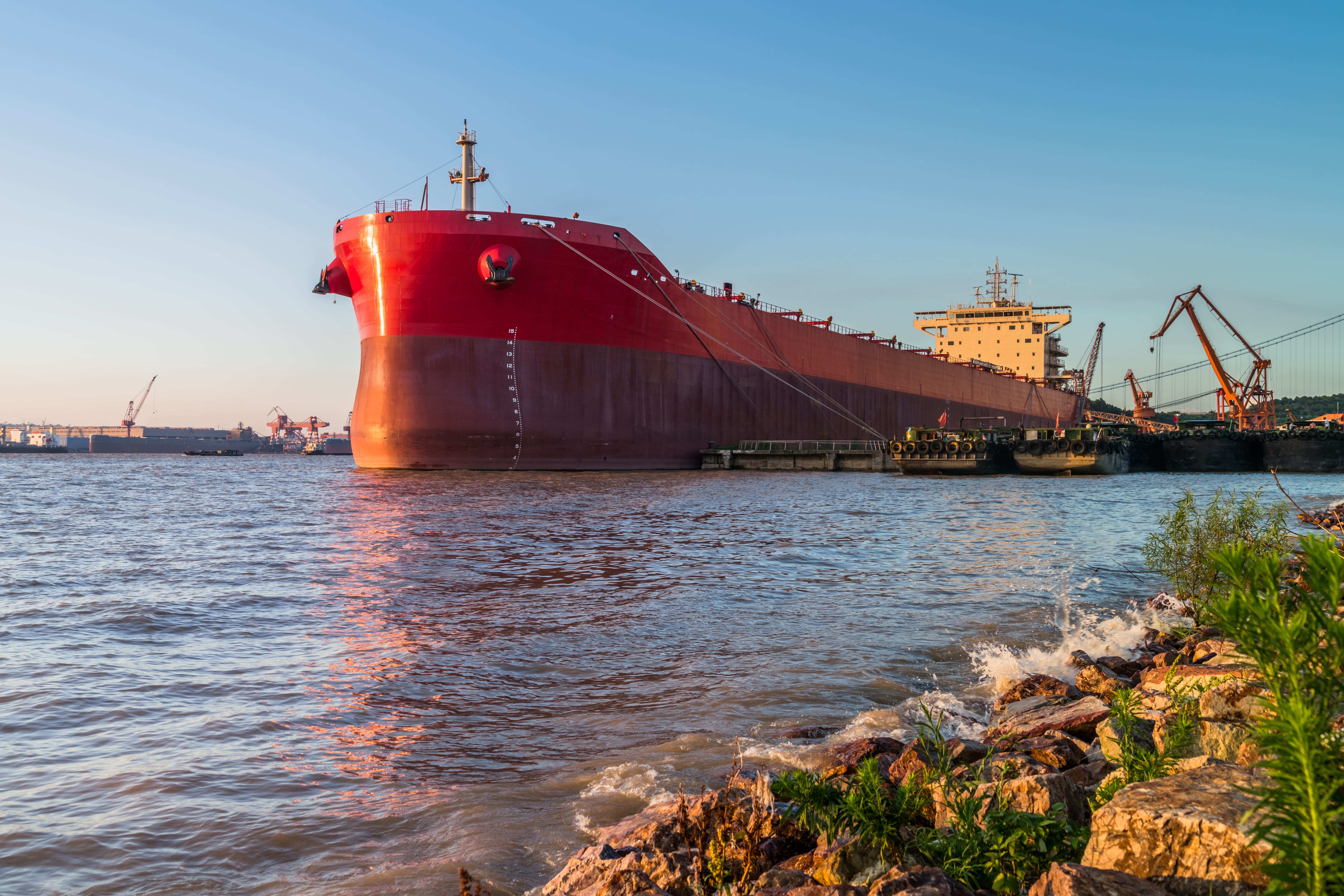 Large red freight ship sailing on top of an ocean.