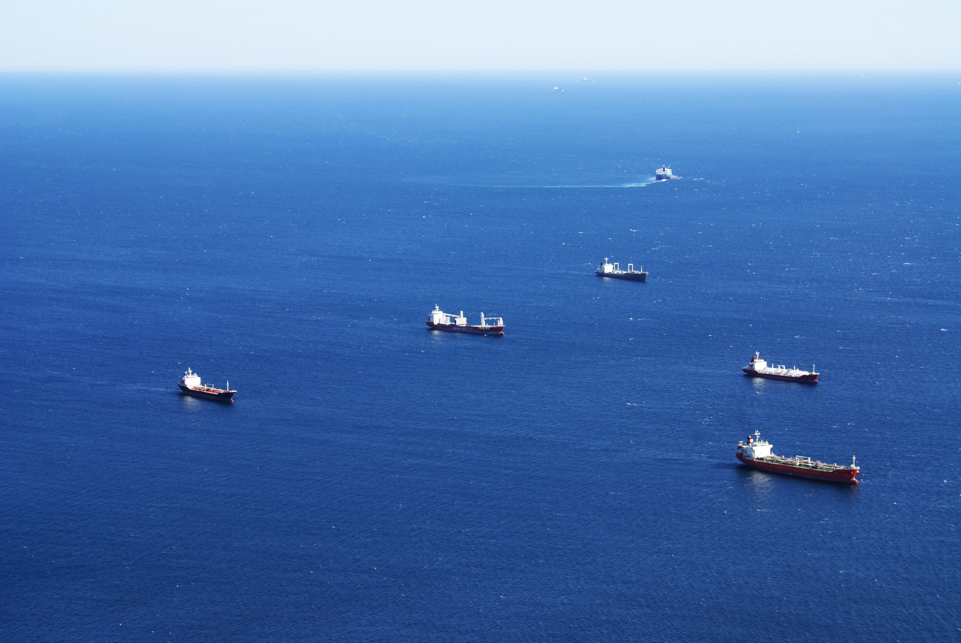 Fleet of freight ships sailing above a blue ocean.