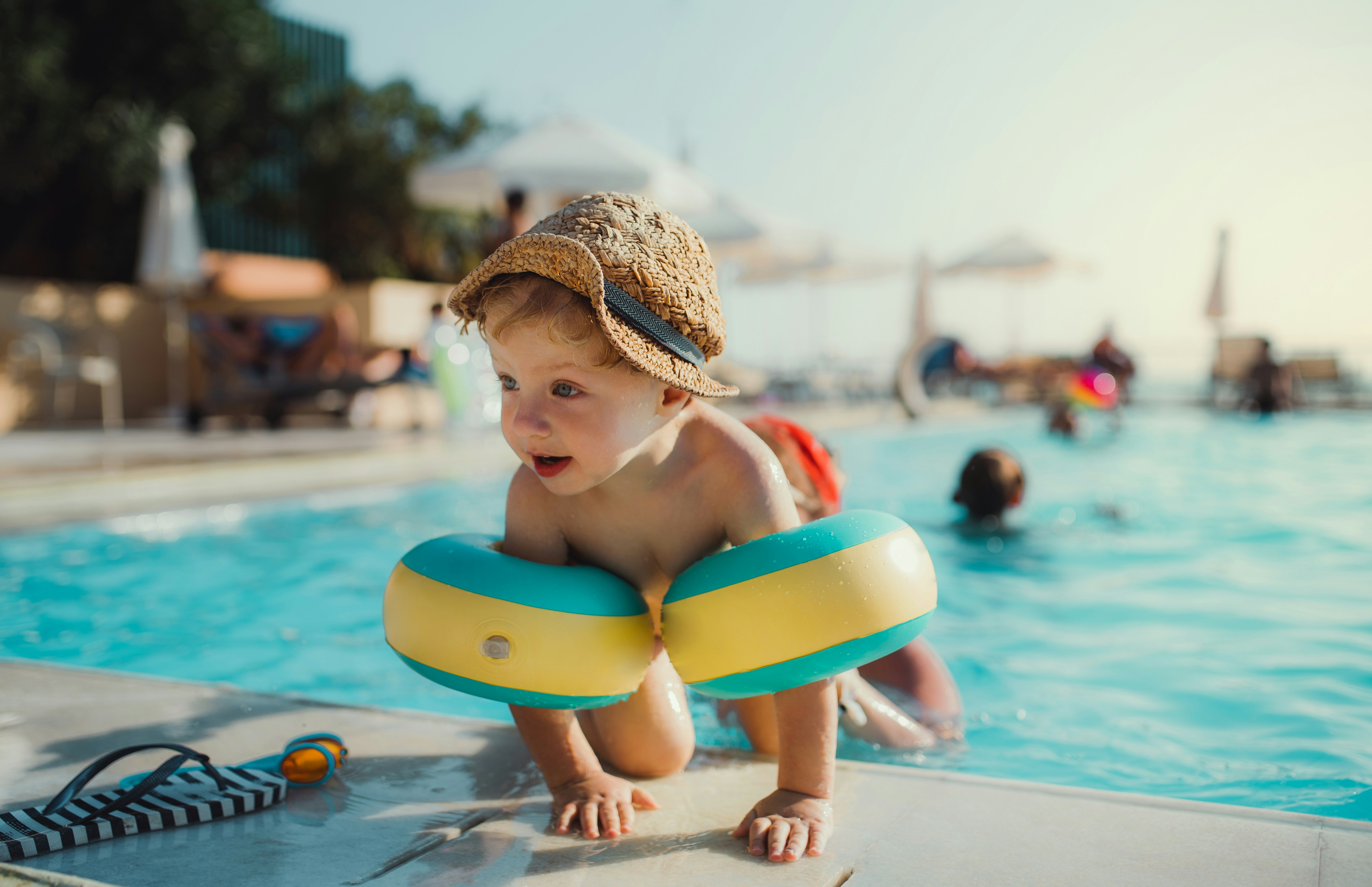 Image of a small child wearing floating aids coming out of a swimming pool