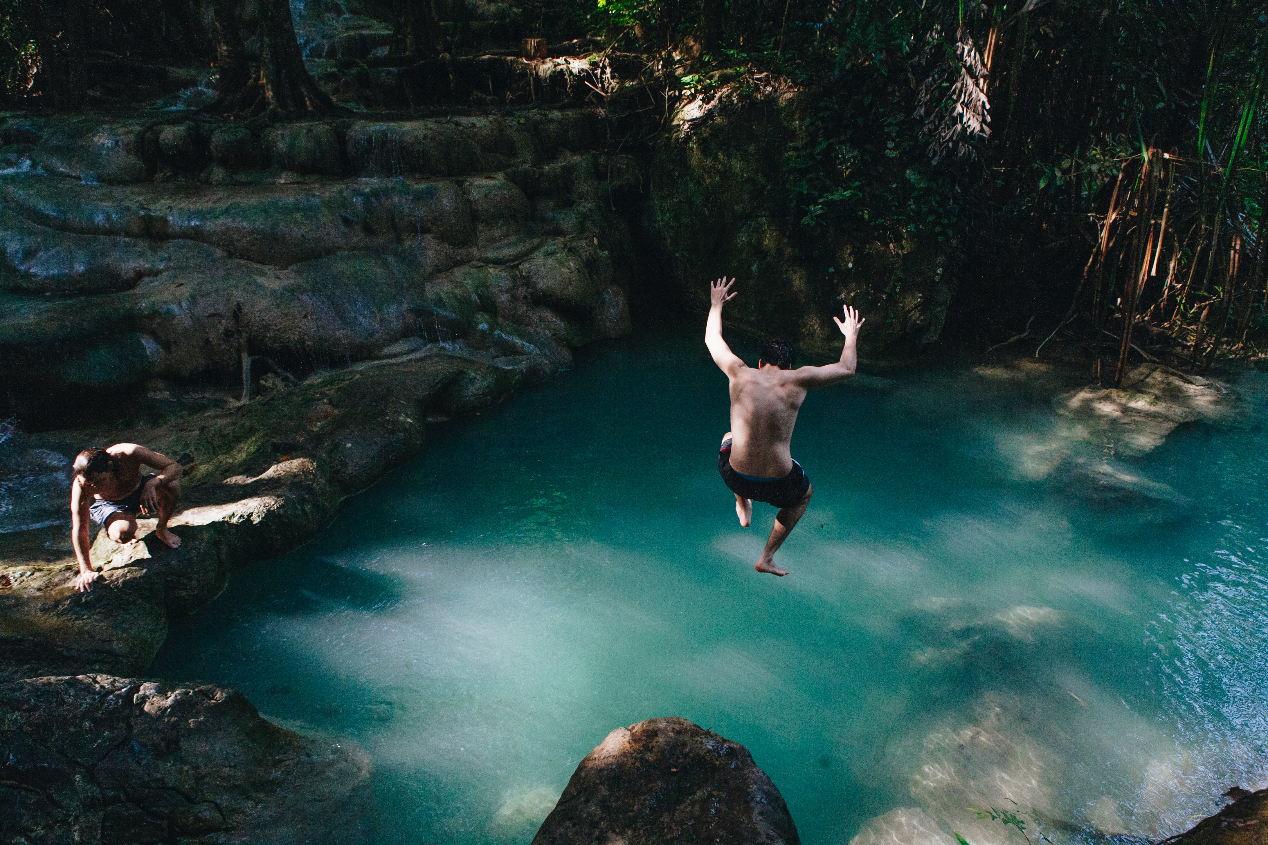 Person jumping off a rock into a river