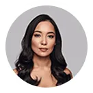 Portrait of a woman with long dark hair and a neutral expression against a gray background.