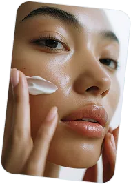 Close-up of a woman applying moisturizer on her cheek with her fingers.