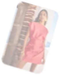 Woman in a red dress standing by a brick pillar outdoors.