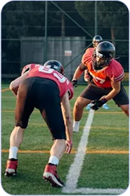 Two American football players in red and black uniforms facing each other on a field marked with white lines during a game or practice.