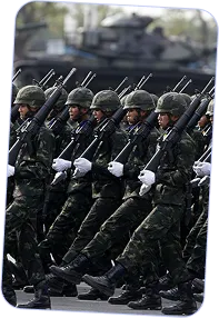 Soldiers in camouflage uniforms and helmets marching in formation while holding rifles with bayonets.