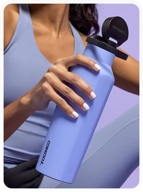 Person holding a matte lavender Corkcicle water bottle with a black lid, dressed in light blue athletic clothing.