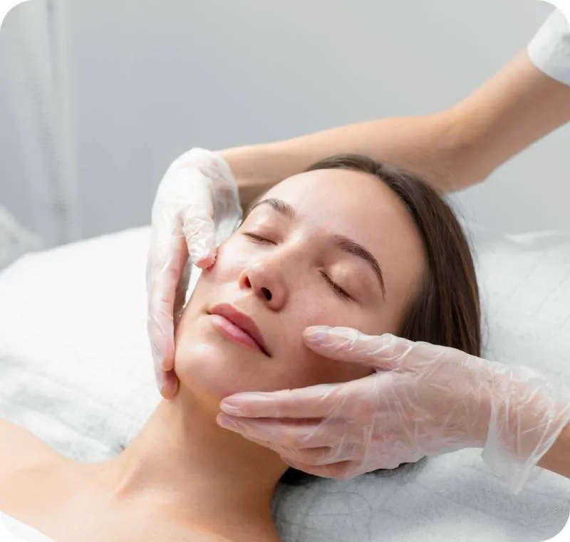 a photo of a woman laying on her back and receiving a face massage as part of facial treatment