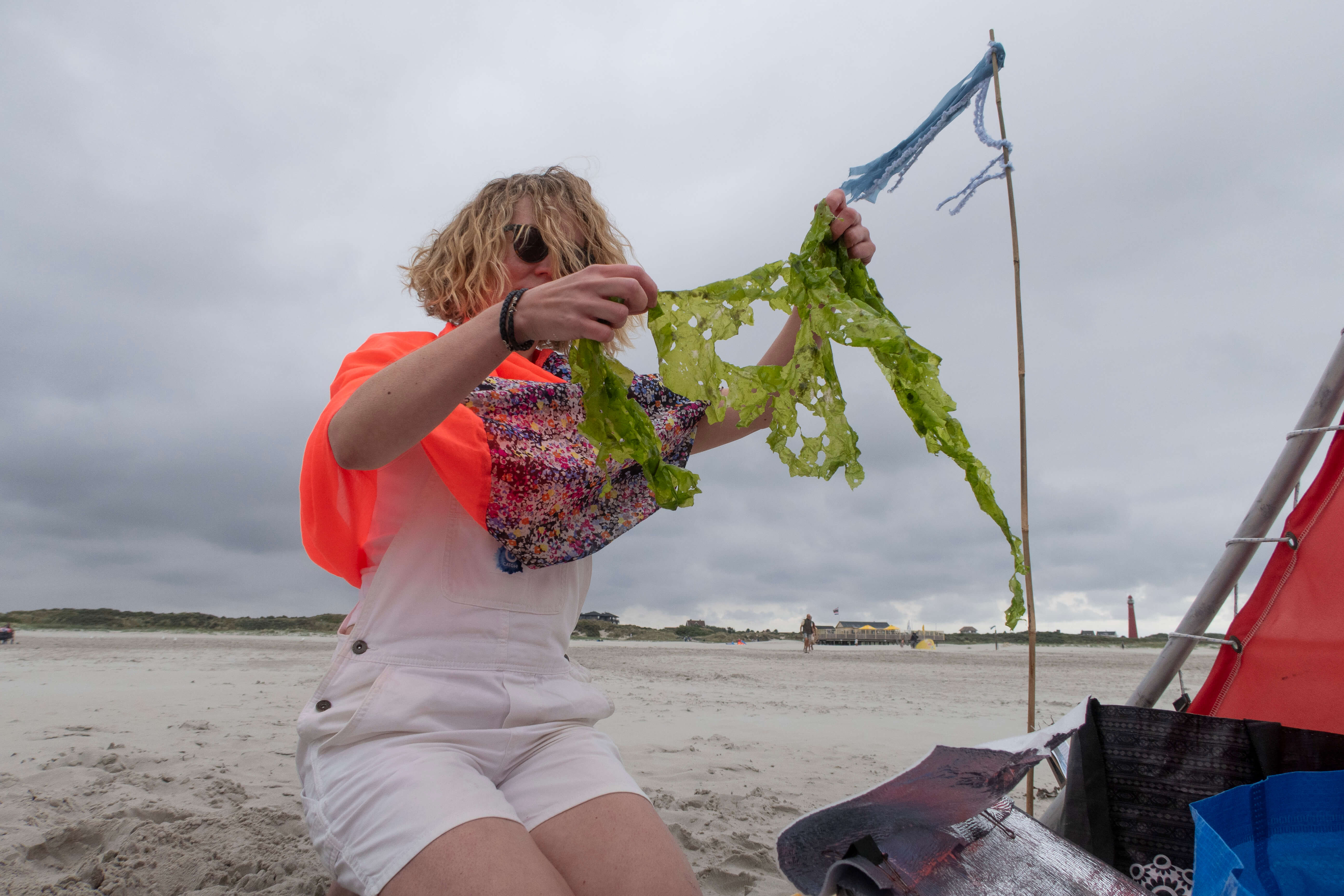 Francisca houdt zeesla omhoog om het op een UV gevoelig papier te leggen op het strand op Schiermonnikoog